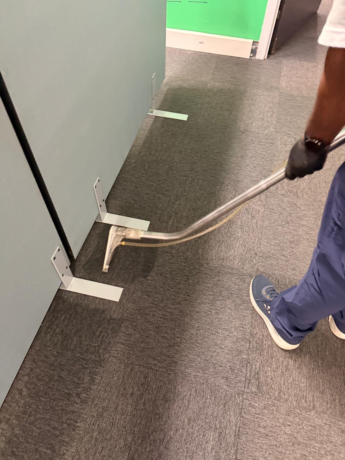 Carpet cleaning wand working along the base of office partitions
